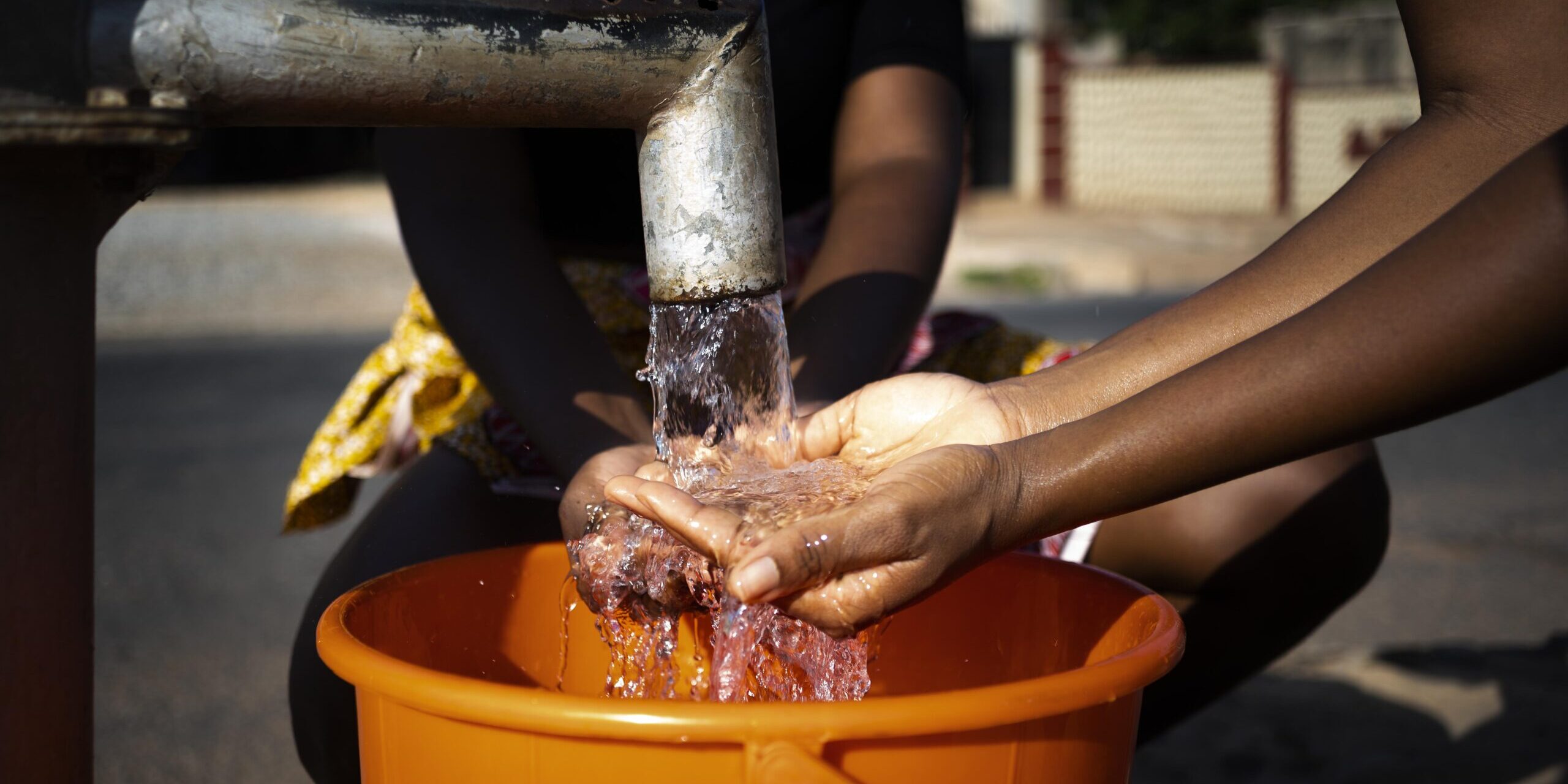 african-woman-pouring-water-recipient-outdoors