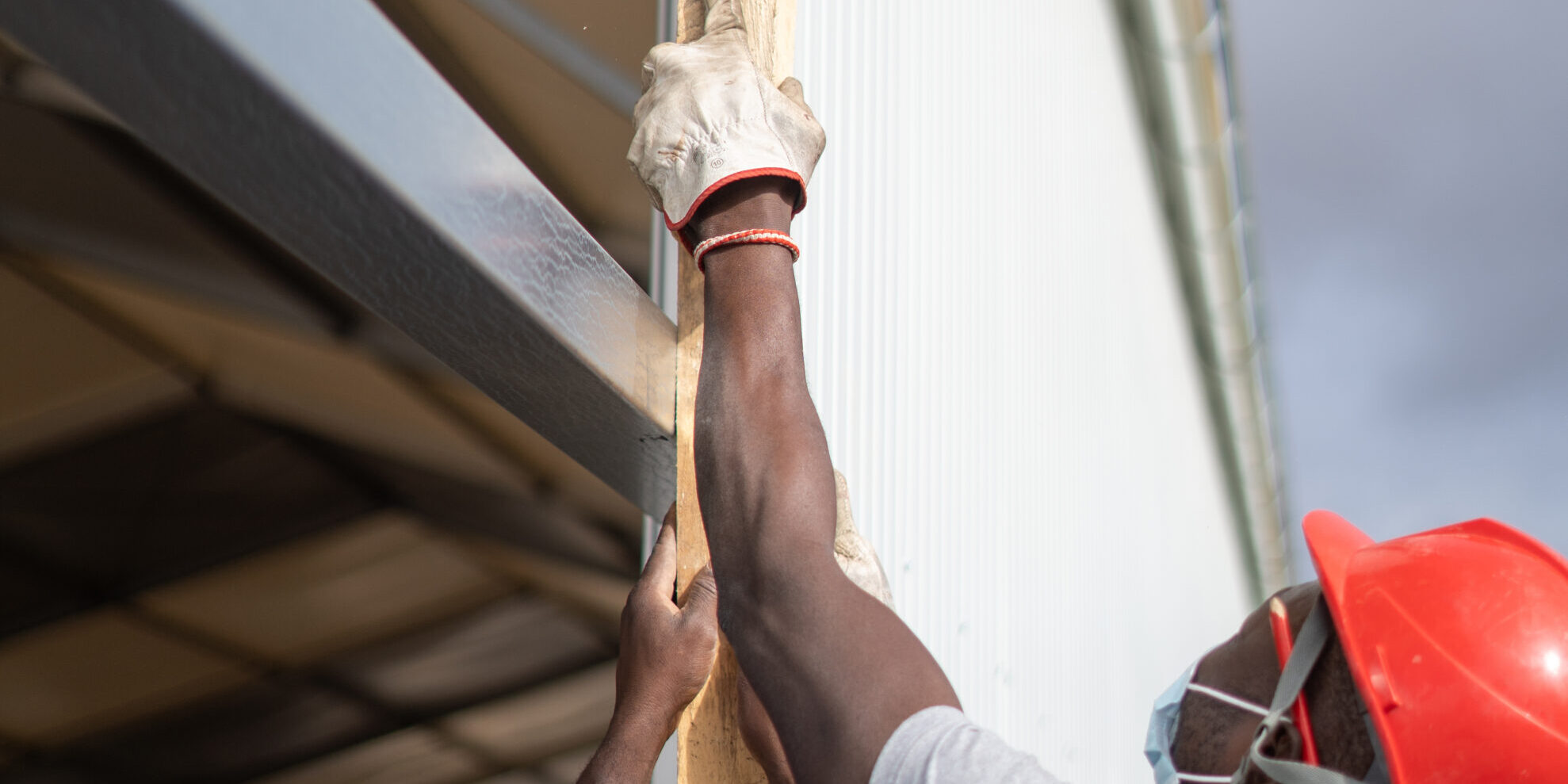 Afro-American builders wearing helmets and face masks while measuring the wall